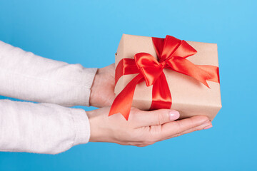 Present box with red ribbon in hands.