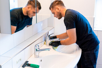 man cleaning a bathroom sink with a scraper blade and micro fiber cloth to remove lime and stains