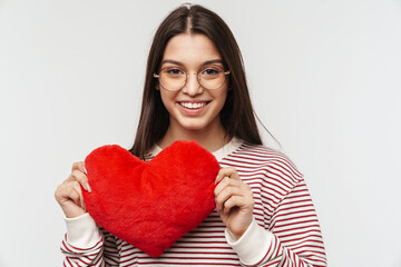 Photo of happy young woman smiling and holding heart shaped pillow