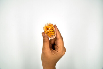 Close up of hand holding corn flake biscuit over white background