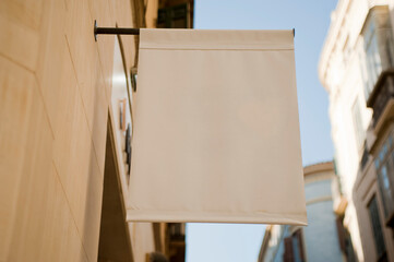 Blank signboard store mockup on a yellow wall, blue sky and buildings in the background