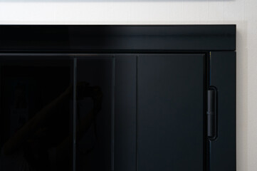 Glossy black metal entrance door with details: handle, open closed lock, hinges and threshold.