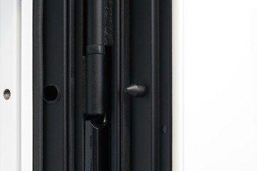 Glossy black metal entrance door with details: handle, open closed lock, hinges and threshold.