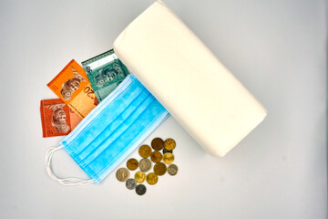 Surgical face mask, bank notes and tissue role over white background