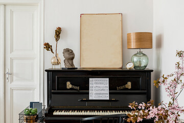 Modern concept of mock up poster frame with design black piano, table lamp, gold clock, dried flowers in vase and elegant personal accessories in stylish home decor.