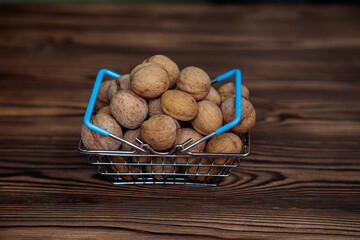 A basket full of inshell walnuts on a wooden background. Natural, healthy product. Space for text.
