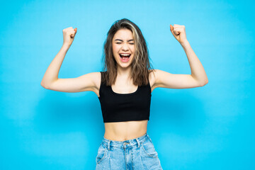 Young girl make winner gesture standing isolated over blue background