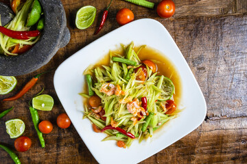 .Cooking Thai food, papaya salad and papaya salad in a dish with a serving on a wooden table.