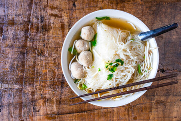 .Noodle and meatballs in a bowl on a wooden table