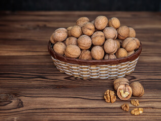 A basket full of inshell walnuts on a wooden background. Natural, healthy product. Space for text.