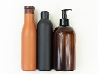 empty dark plastic bottles of soap and shampoo lie on a light background