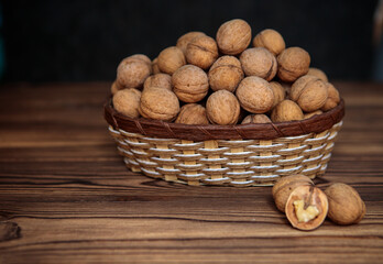 A basket full of inshell walnuts on a wooden background. Natural, healthy product. Space for text.