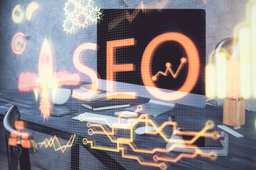 Multi exposure of table with computer and seo drawing hologram. Search optimization concept.
