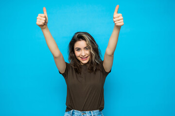 Portrait of beautiful woman with thumbs up on blue background