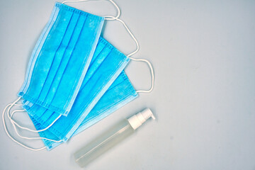 Hand Sanitizer and surgical face mask over white background