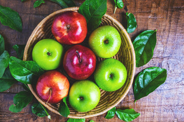 .Green apple and red apple in a basket on a wooden background