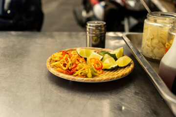 Traditional Vietnamese noodle condiment tray with dish of lemon slices, jar of chili, fish sauce, soy sauce, spoons and chopsticks at street food cart in Ho Chi Minh city, Vietnam