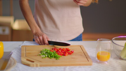 Housewife slicing vegetables on wooden board at kitchen. Lady eating tomato