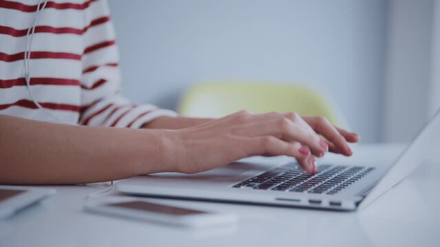 Close up of young female hipster hands working online on latop in bright work space. Remote work concept
