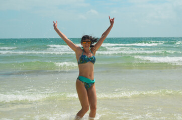 Young millennial girl in a swimsuit is having fun and enjoying life on vacation at the sea