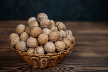 A basket full of inshell walnuts on a wooden background. Natural, healthy product. Space for text.