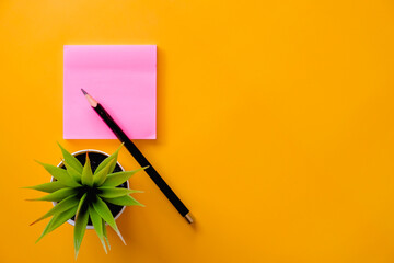 Black  pencil and pink note paper on yellow background