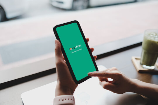 Bangkok. Thailand. MAY 25,2020: Woman hands using tripadvisor app on smart phone for booking the apartments or hotel and searching interesting place. Close up. Indoor shoot.