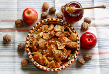 Baked apples in a plate with honey and walnuts on the table
