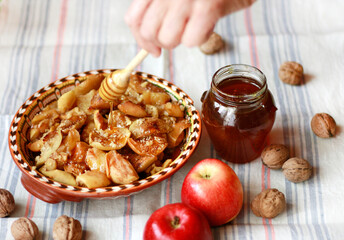 Baked apples in a plate with honey and walnuts on the table