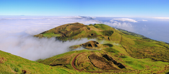 Panoramic view of green landscape above the clouds with grass and ocean at the island of Sao Jorge, Azores, Portugal