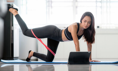 Online sport fitness yoga training workout. young woman and doing exercises on yoga mat by laptop at home