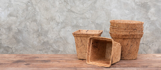 Ecology flower pots made from coconut fiber on wooden table with cement wall background