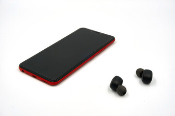 Mobile phone and wireless earphone over white background