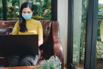 Asian women wear yellow shirts to work on holidays. Asian girl wearing mask, doctor sitting and working online During the outbreak of the Coronavirus infection or Covid 19.