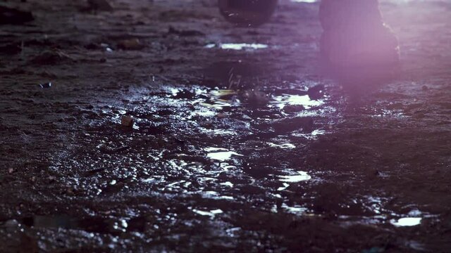 Feet of soldier in army boots moving forward in mud and puddle. Soldier stepping into the muddy puddle at night. The ranger's legs move forward. Steps of a soldier entering an industrial premises