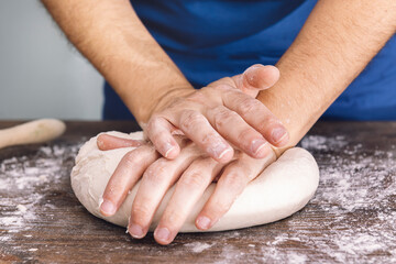Fototapeta premium hands of a woman kneading dough on a wooden table