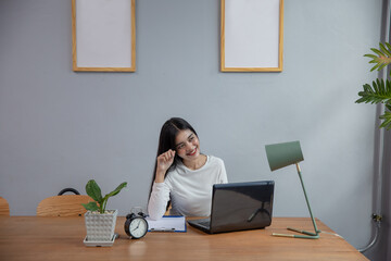 asian young woman working on laptop computer black sitting at the living room in the house.social...