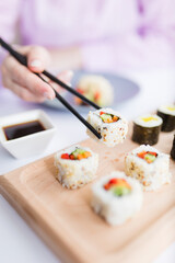 Close up of female eating sushi portion roll with chopsticks at restaurant.