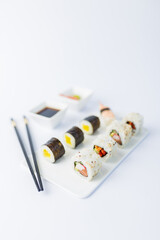 Sushi rolls and nigiri meal set with chopsticks, soy sauce, wasabi and gari on table.