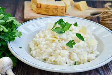 Italian creamy  cheese risotto with parmesan cheese and fresh basil on rustic background