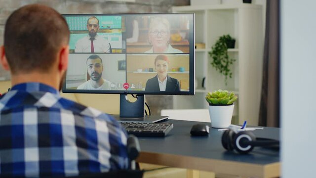 Businessman in wheelchair waving during a video call with business partners. Handicapped invalid paralysed freelancer, immobilized entrepreneur working from home, ilness and disability