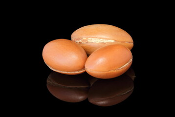 Isolated photo of some argan nuts reflected with black background.