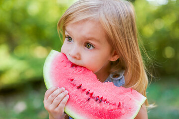Child eating watermelon in the garden. Kids eat fruit outdoors. Healthy snack for children. 2 years...