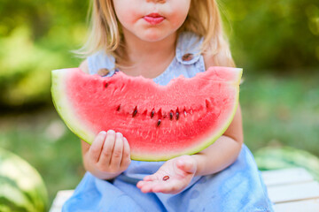 Child eating watermelon in the garden. Kids eat fruit outdoors. Healthy snack for children. 2 years...