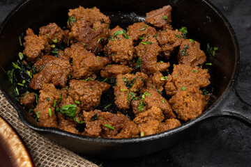 Seitan fried in cast iron pan with herbs and spices