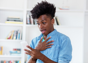 African american young adult receiving message with bad news on phone