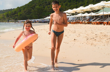 Happy  beautiful caucasian children on vacation on a sandy beach. Brother and sister having fun together. Concept summer lifestyle