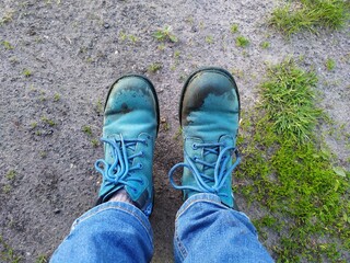 Dirty blue shoes and jeans on ground with green grass