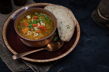 Vegan vegetable soup and bread in bowl on dark table