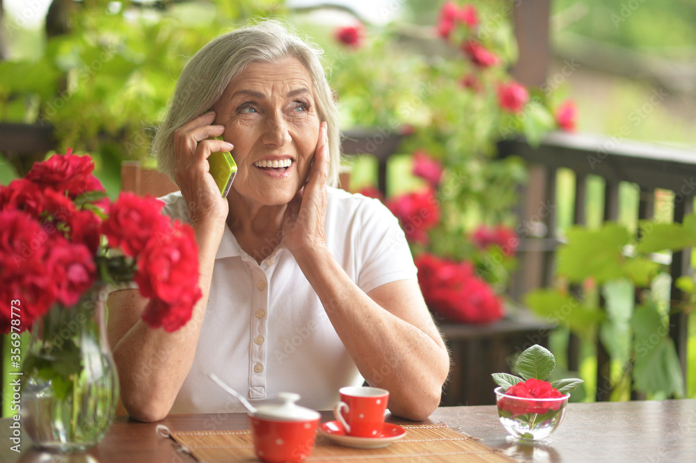 Poster Portrait of a happy aged woman talking on smartphone